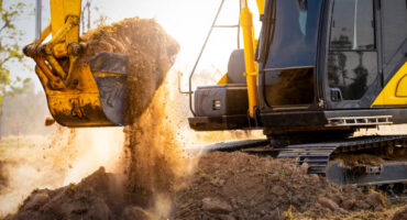 Close-up of excavator at construction site. Backhoe digging soil for earthwork and construction business. Excavating machine at work. Heavy machinery for earth moving and construction site development